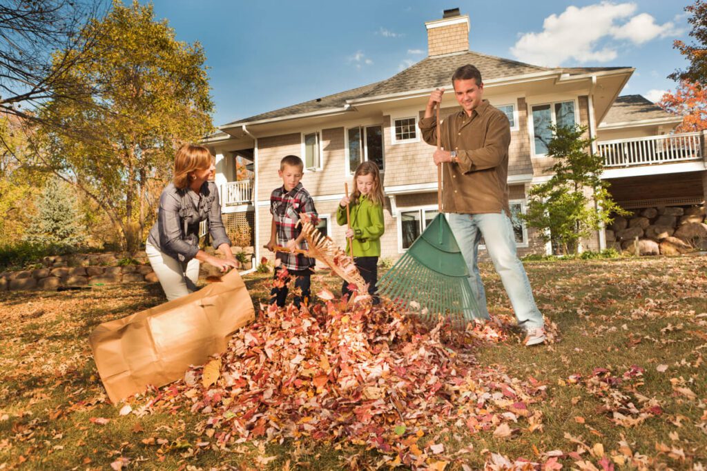 Family Doing Autumn Outdoor Leave Raking Work Together